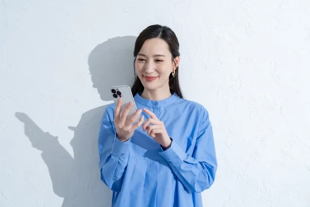 携帯を触る青いワンピースを着た女性