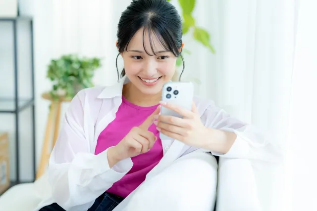 ソファーに座りスマホを見ている女性