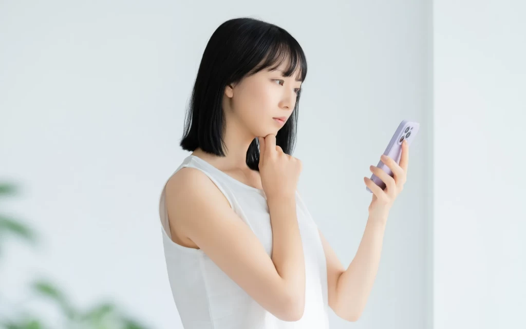 スマホを見て悩んでいる女性