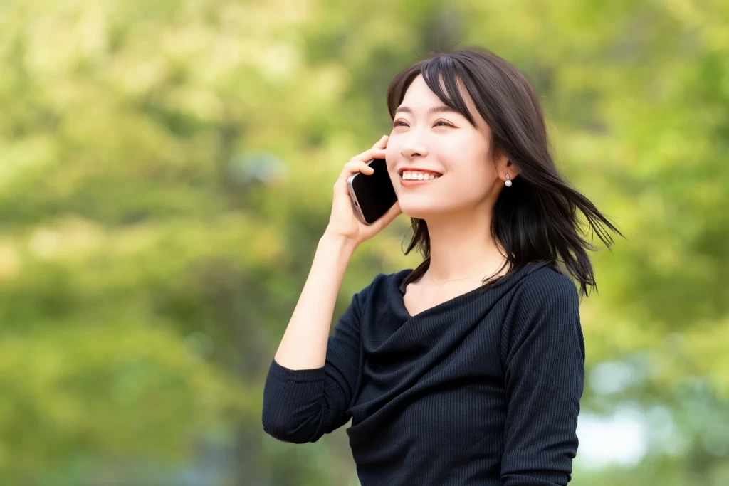 スマートフォンをで通話しながら笑う女性