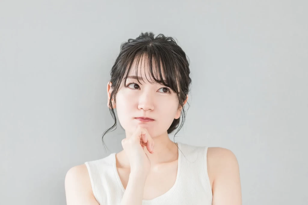 顎に手をあてて上を見ながら悩む女性