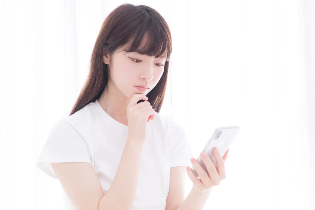 スマートフォンを見て考え込む女性