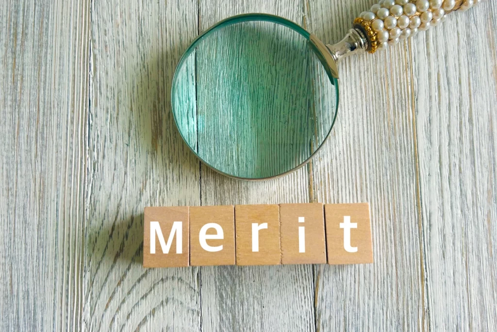 メリットと書かれたブロックとルーペ