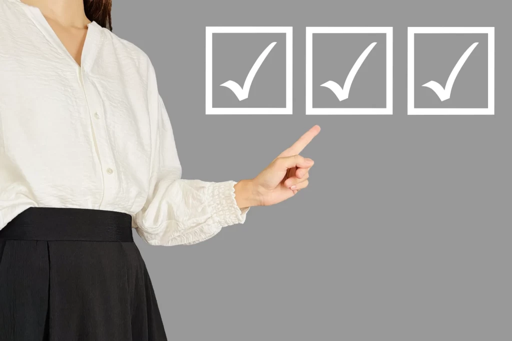 3つのチェックマークを指さす女性