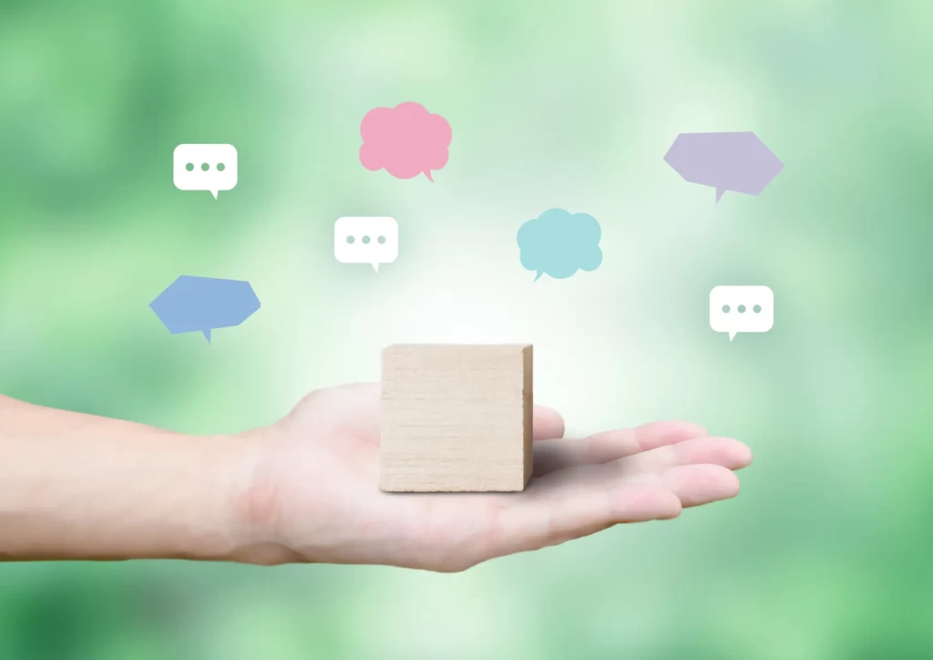 女性の手のひらに乗せた木製ブロックと、口コミを表す7つの吹き出し