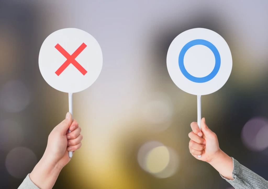 〇と✕が表示された札を持つ手