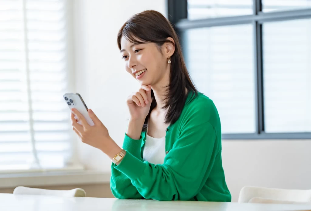 スマホの画面を見つめながら微笑む若い女性