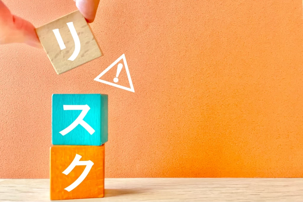 リスクの文字が表示された木製ブロックと注意のマーク